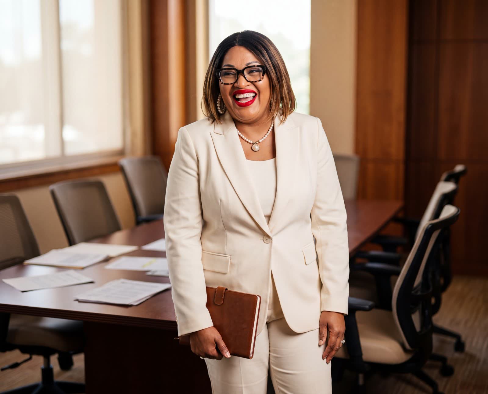 Dr. Martha Liddell smiling in a boardroom, holding a leather portfolio.
